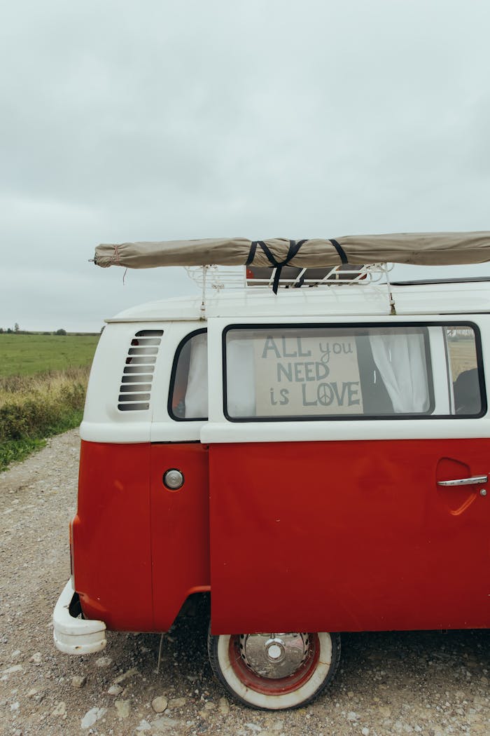 about-us-02 A retro red van parked on a rural road with an inspirational 'All You Need Is Love' message.