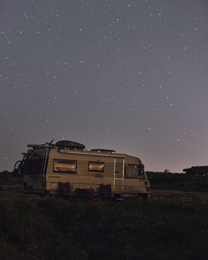 about-us-01 A serene night sky full of stars over a parked camper in a quiet wilderness setting.