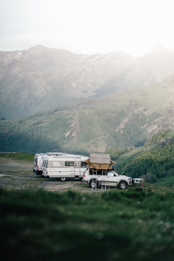 services-03 A car and camper van set up camp in a serene mountainous landscape, perfect for an adventurous escape.