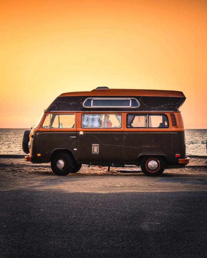 services-01 A classic Volkswagen campervan parked by the sea during a vibrant sunset.