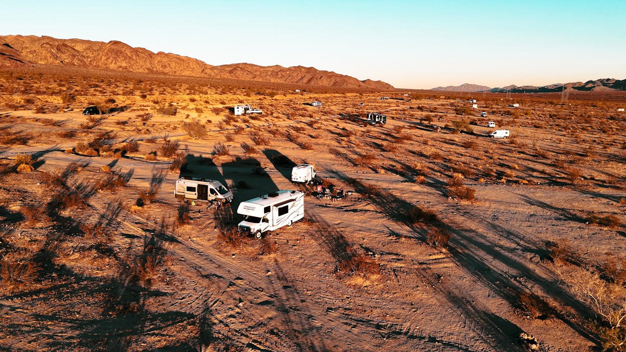 home-hero-2 Aerial shot of RVs camped in a desert landscape at sunset, highlighting adventure travel.