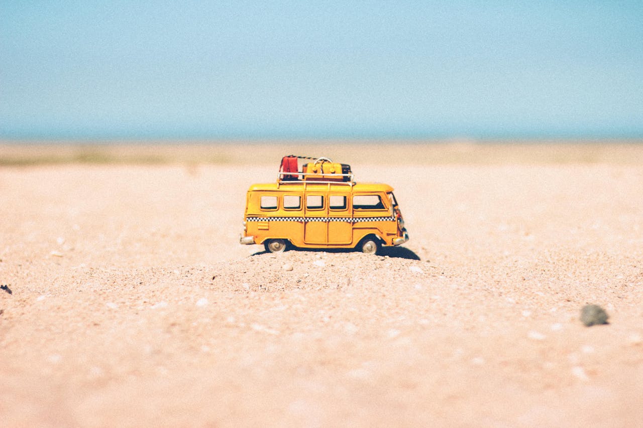 services-02 A toy van on a sandy beach evokes summer travel and vacation vibes.